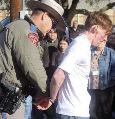 Blake Helms is handcuffed by a DPS trooper after failing a field sobriety test. Sticker Photo By Darrell Vyvjala