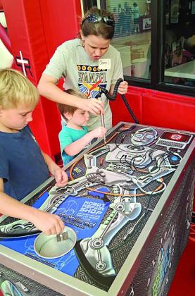 At the Robot Repa ir STEM challenge, Stanzel Family Foundation CEO Cheryl Pekar (right) helps her son Kaiden (standing next to her) and another attendee strengthen focus and fine motor skills.