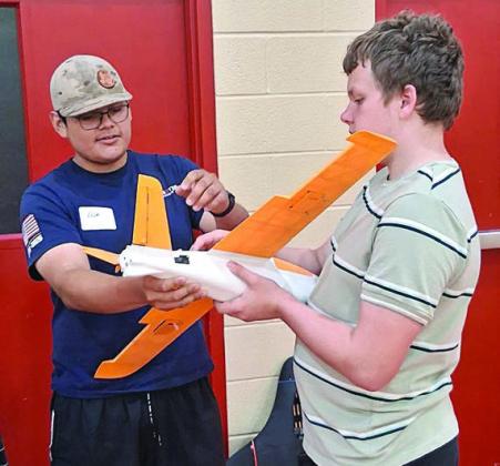 A model aircraft that was 3D printed by Noe Nieto (left) is being shown to an attendee.