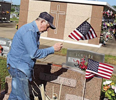 Flags are being placed on the graves of Johnnie and Livia Tumis at St. Rose of Lima Cemetery by Harry Bartosch. Johnnie Tumis (Dec. 3, 1917-Jan. 17, 2007) was a staff sergeant in the U.S. Army during WW II and received the Purple Heart. Livia Tumis (May 21, 1921-May 22, 2011) was a Legion Auxiliary member.