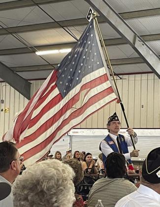 Post 143 First Vice Commander Ed Semler waves a tattered flag while the song “Ragged Old Flag” by Johnny Cash plays. Sticker Photo By Darrell Vyvjala