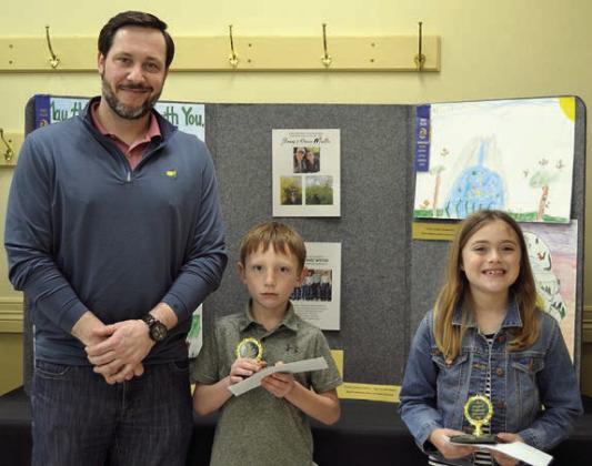POSTER CONTEST winners in Division 1 (grades K-2) were Cason Peschke (center) of Sacred Heart School in La Grange and Sylvia Shimek (right), also of Sacred Heart School in La Grange. Presenter was Bryan Minzenmeyer (left) of Fayetteville Bank.