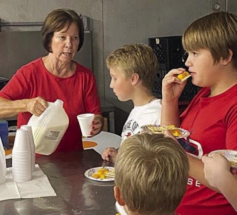 Serving fresh milk to Brennen Berger (second from right) and Noah Heger (right) is Darlene Stryk (right).