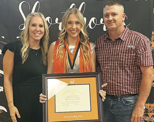 Reagan Dusek (center) accepts the salutatorian plaque and medal with her mom, Renee, and dad, Michael, on hand last Thursday. Sticker Photo By Darrell Vyvjala