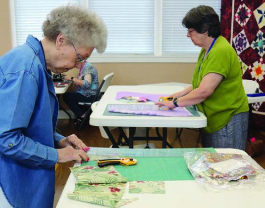 Cutting quilt blocks are Kay Marburger and Kathi Babcock.