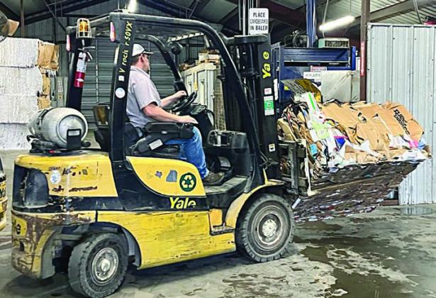 A bale of cardbo ard is being moved by Gary Eudy, recycling attendant.