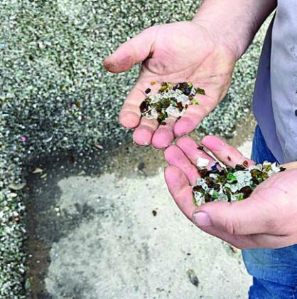 Some of th e SMOOTH glass gravel produced on-site is being held by Gary Eudy, recycling attendant. The glass gravel does not have sharp edges and can be used for gardens, yards and driveways.