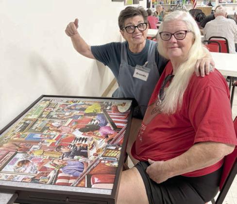 Showing off the puzzle that was completed after many hours of work by many people are (from left) volunteer Brenda Ray and member Kelly Ortiz.