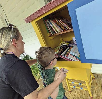 At the Melinda Stanzel Barneycastle Little Free Library, SISD kindergarten teacher Kacy McBride assists a student.
