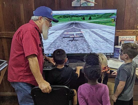 Instructing students on how to use the flight simulator is Stanzel docent David McCall.