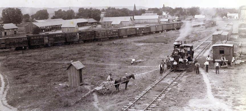 Circa 1895 photograph of the M.K.T. rail yard on the eastern end of La Grange (vicinity of 600th block East La Fayette Street) looking south with the bluff in the distance. Louis Melcher captured this view from the roof of the M.K.T. freight depot. Train cars, warehouses, elevated tanks and open sheds like those used by lumberyards are visible (present day Farmer’s Lumber Co.).