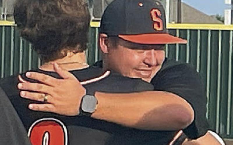 With the final score posted on the scoreboard, head coach Marty Bigham hugs Jayse Janda, one of his five seniors. Sticker Photo By Darrell Vyvjala