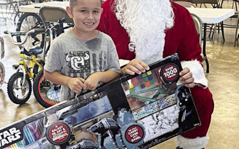 A young man poses with Santa (Investigator Jeremy Castleberry) during last year’s toy pick-up in Flatonia.