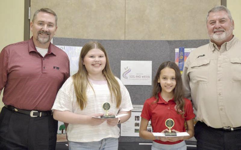 POSTER CONTEST winners in Division 2 (grades 3-6) were Emma McCourt (second from left) of St. Rose of Lima Catholic School in Schulenburg and Sophie Janda (second from right) of Sacred Heart School in La Grange. Award sponsors were National Bank &amp;amp; Trust, represented by Scott McManus (left), and Fayette Savings Bank, represented by Mark Friedrich (right).