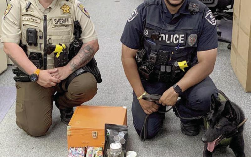 Sheriff’s Department Deputy Josh Jones (left) and Schulenburg Police Department Officer Byron Powe with his canine partner, Semper, are shown with the items found after a traffic stop last Wednesday on Highway 71.