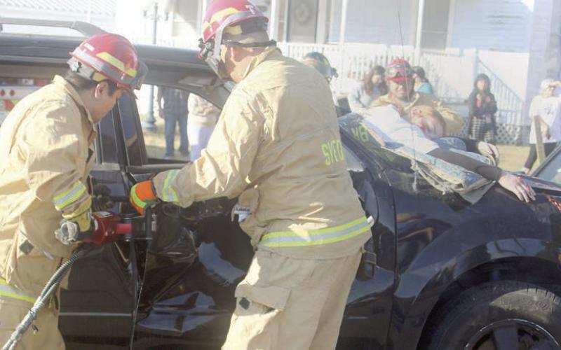 Firefighters use extrication tools to remove the door of the vehicle from which Katry Kobza was ejected through the windshield and later pronounced “deceased.” Sticker Photo By Darrell Vyvjala