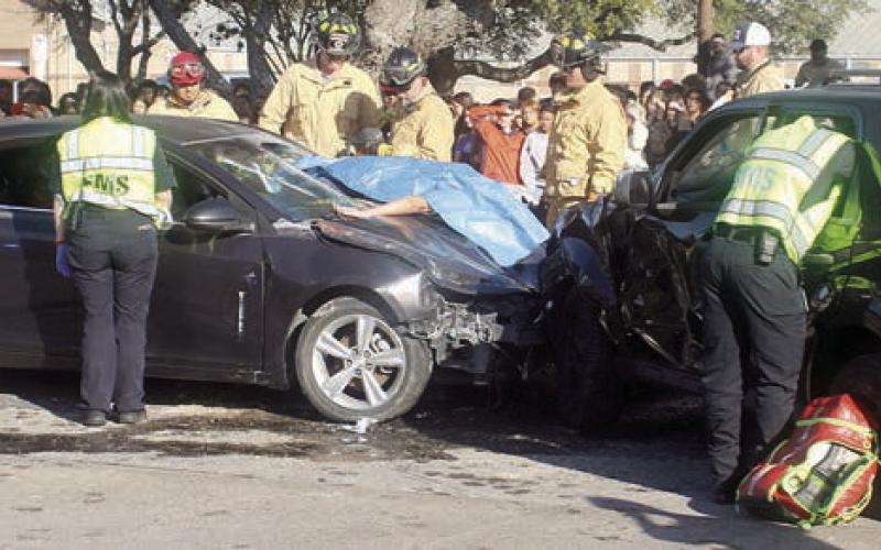 DPS troopers, EMS personnel, and firefighters work the mock accident scene as high school students look. Sticker Photo By Darrell Vyvjala