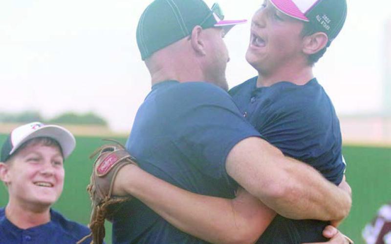 Brayson Prihoda (right) get a hug from coach Josh Morgan following the final out Wednesday with Josh’s son, Nolan (left) coming to join the celebration. Sticker Photo By Darrell Vyvjala
