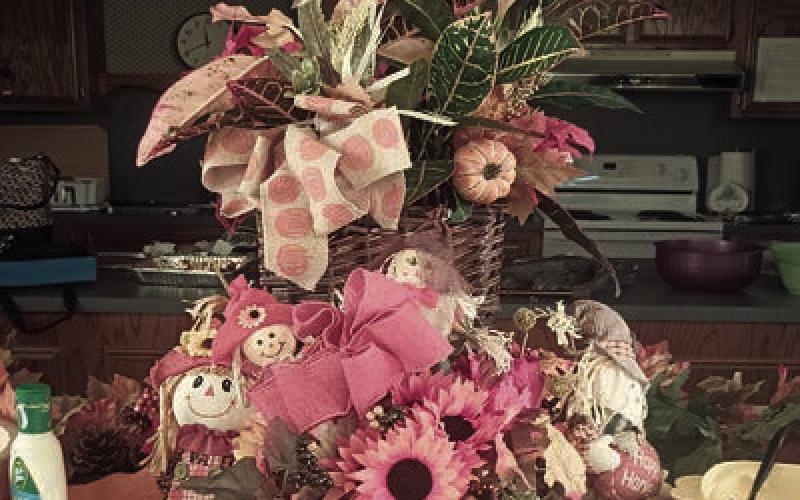 Hostesses for the Garden Club meeting were (from left) Jan Ripper, Wanda Brown and Mary Demel. At right is the centerpiece, which carried out the autumn theme with decorations that included burlap cloths, croton plant, pumpkins and scarecrows.
