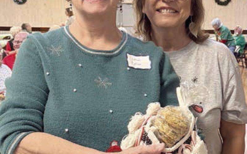 Successfully guessing the number of home-baked cookies in this darling stocking in a game brought by volunteer and board member Cynthia Trojacek (right) was Janiece Collins (left).