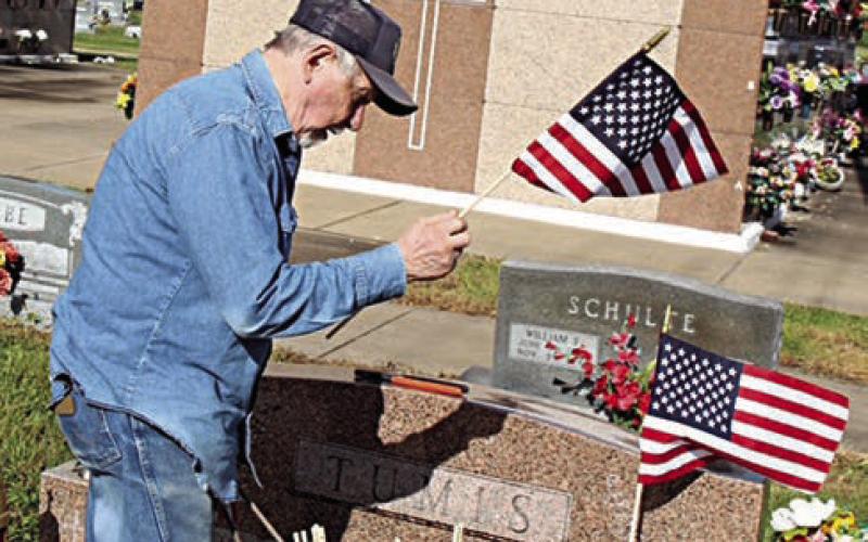 Flags are being placed on the graves of Johnnie and Livia Tumis at St. Rose of Lima Cemetery by Harry Bartosch. Johnnie Tumis (Dec. 3, 1917-Jan. 17, 2007) was a staff sergeant in the U.S. Army during WW II and received the Purple Heart. Livia Tumis (May 21, 1921-May 22, 2011) was a Legion Auxiliary member.