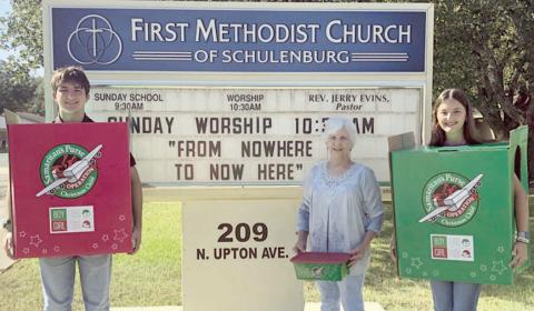 Samaritan’s Purse “Operation Christmas Child” boxes are being held by (from left) Nick Rorschach, Margie Gresham and Molly Rorschach in front of the First Methodist Church of Schulenburg sign. The project solicits shoeboxes filled with items to be distributed to children around the world.