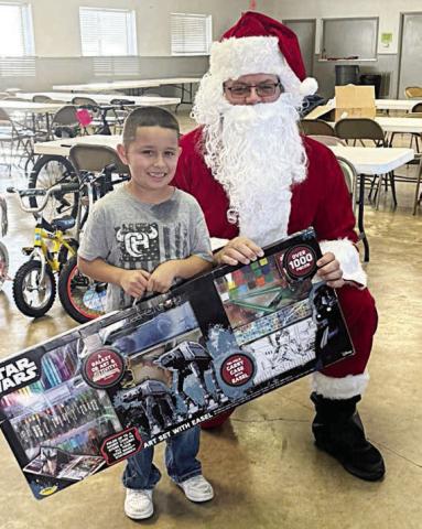 A young man poses with Santa (Investigator Jeremy Castleberry) during last year’s toy pick-up in Flatonia.