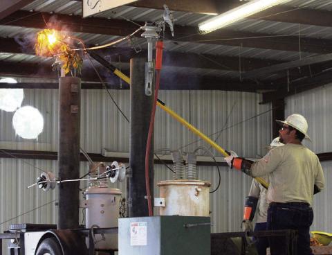 Fayette Electric Cooperative lineman Justin Whited demonstrates what could happen when tree limbs touch a power line.