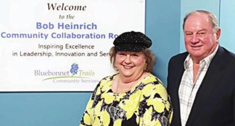 BOB HEINRICH COMMUNITY COLLABORATION ROOM – Robert L. “Bob” Heinrich and his wife Diana stand beside the sign that designates a room at the new Bluebonnet Trails Community Service building in his honor.