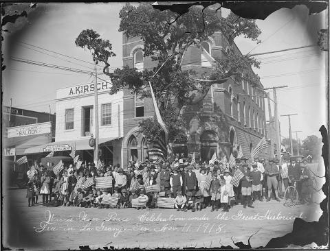 Louis Melcher’s photograph of a large group, including schoolchildren, holding American flags under La Grange’s Historic Oak, which is draped in patriotic bunting. The emulsion is pulling away from the edges of this glass negative on which was written: “War-is-Won-Peace-Celebration under the Great Historical Tree in La Grange, Tex. Nov. 11, 1918.”  Courtesy of Fayette Heritage Museum & Archives