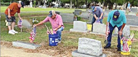 From left: C.W. Leonard, Wesley Holub, Delvin Dieringer and Stanley Kubenka mark the graves of deceased veterans with flags at the Schulenburg City Cemetery.