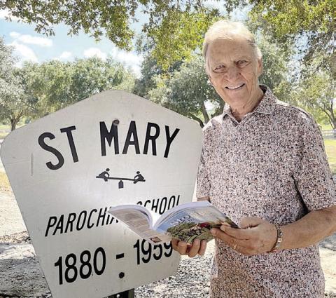 Willy Schmidt shared his memories of attending St. Mary Parochial School at High Hill, along with his classmate and childhood neighbor Cleo Dittrich Wenske, in Stories I’ve Been Told – Volume 4. He expects his story to live on for generations and become a family heirloom. Willy is pictured taking his first look at the book beside the sign marking the location of his first school.