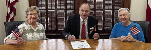 KJZT Family Life representatives Helen Faldyn (left) and Lillian Kallus (right) were on hand as Fayette County Judge Dan Mueller (center) signed a proclamation declaring June 14 as National Flag Day.