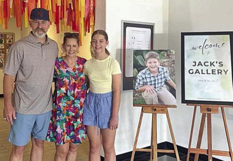 Turtle Wing Foundation was established in honor of Jack Hooper, son of Chris and DeeAnn Hooper. Jack, who had been diagnosed with high-functioning autism at age 6, passed away on April 5, 2011. Shown are (from left) Chris and DeeAnn Hooper and their daughter Cate Hooper. A portrait of Jack Hooper is placed between the family and the Jack’s Gallery sign.