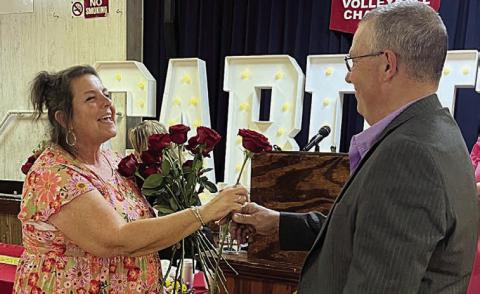 Donna Kunz (left) receives the last of 40 roses representing her 40 years at St. Rose from her husband, Darren.