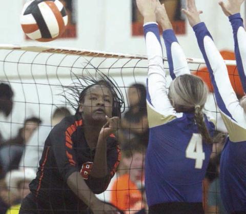 Jessalyn Gipson follows through on a kill off the top of the net away from two Louise blockers in game three. Sticker Photo By Darrell Vyvjala