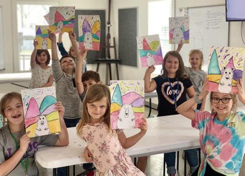 In the Arts for Rural Texas art after-school program at the Fayetteville campus, students display artwork created during a previous session. In this lesson, the students learned about artist Ted Harrison and created work inspired by his bright and colorful landscape paintings of the Yukon.