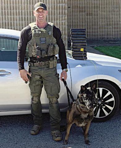 Sgt. Randy Thumann and Kolt pose in front of the Nissan Altima and the packages of cocaine they found after a traffic stop.
