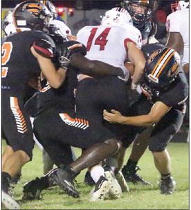Bryce Stoever (right) and Rodney H Walton wrap up Colby Beck in the second quarter with John Davis (left) closing in to help make the fourth-down stop. Sticker Photo By Layne Vyvjala