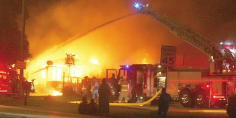 The SVFD’s ladder truck sends down a heavy stream of water to help get Tuesday morning’s structure fire under control while the Juarez family (center, in the foreground) watch helplessly as their house burns to the ground. Sticker Photo By Darrell Vyvjala