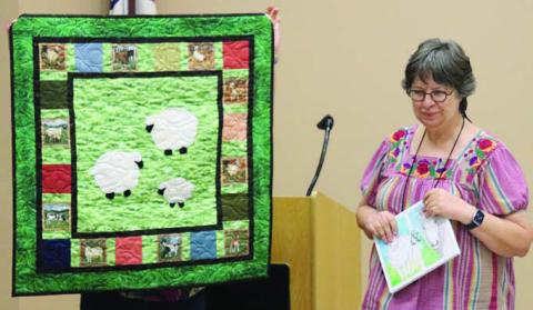 LEFT PHOTO – Sandy Courrier shows her quilt constructed to accompany the children’s book Cheepy and Grandma Mare.