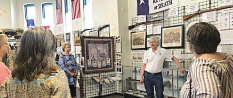 Docent Charles Murray (standing in back) explains significance of wall items at the Texas Heroes Museum in La Grange to a tour group from them Fayette County Retired Teachers’ Association.