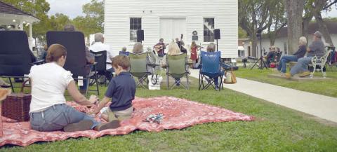 Arts for Rural Texas hosts a free live music series every March and October in Fayetteville on the historic courthouse lawn. Performers from a past series are shown in front of the courthouse while attendees with lawn chairs and picnic blankets enjoy the music.