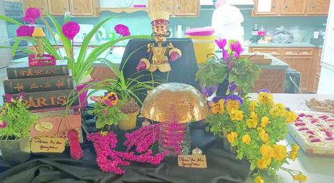 AT LEFT – Hoste sses for the Garden Club meeting were (seated) Billie Rightmer, (standing, from left) Gail Hammontree and Jerry Leonard. cente rpiece reflected the decoration theme, “Paris in the Springtime.” ABOVE – The