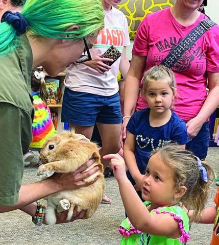 A young lady pets Lulu, held by Desiray Almaraz of The Texas Zoo. Sticker Photo By Darrell Vyvjala