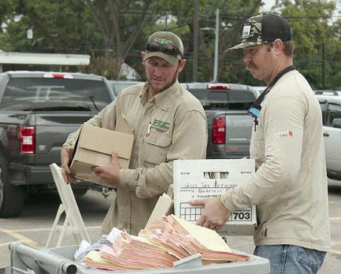 PREPARING DOCUMENTS FOR SHREDDING at last year’s community Shred Day are Fayette Electric Cooperative lineman Corey Brown and lineman apprentice Justin Neiser.