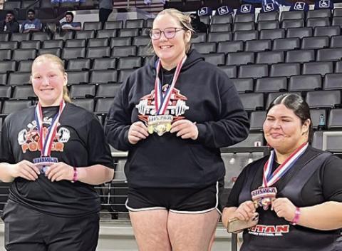 Cora Brenek (center) stands atop the medal stand following her statequalifying performance at the regional meet.