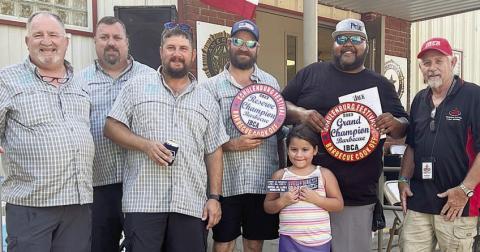 GRAND CHAMPION – “Flying G Barbecue” of Kingsbury, represented by Ira Green (second from right) and Quin Green (front). RESERVE CHAMPION – “JJJ Cookers” of Victoria, represented by (from left) Davis Glass, Mark Svatek, Jared Glass, and Jordan Glass. Also pictured is IBCA offical referee Eddie Myers (right). Sticker Photo By Brandt Vyvjala