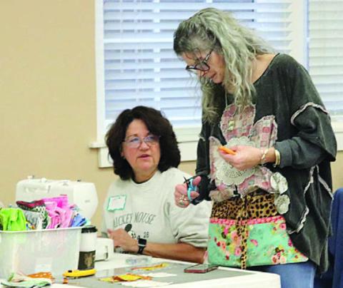 Cutting a strip for Lisa Sandlin (left) is Michelle Lavender (right).
