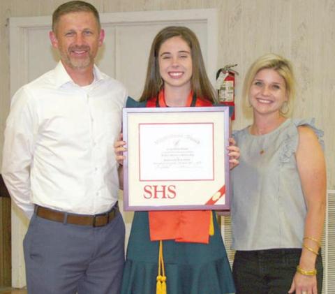 Claire Antosh (center) accepts the valedictorian plaque at the Senior Scholarship and Academic Banquet earlier this month with her parents, Michael Antosh and Erin Bonner. Sticker Photo By Darrell Vyvjala